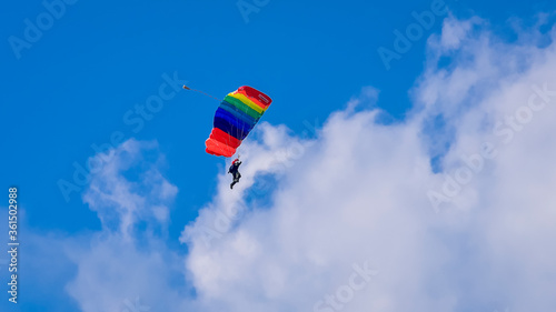 Skydiver and colorful parachute on the blue sky 