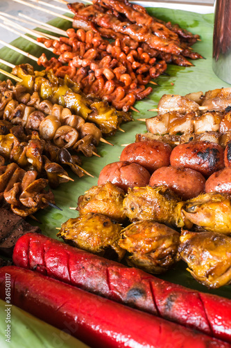 An assortment of popular and exotic Filipino grilled street foods placed on banana leaves. photo