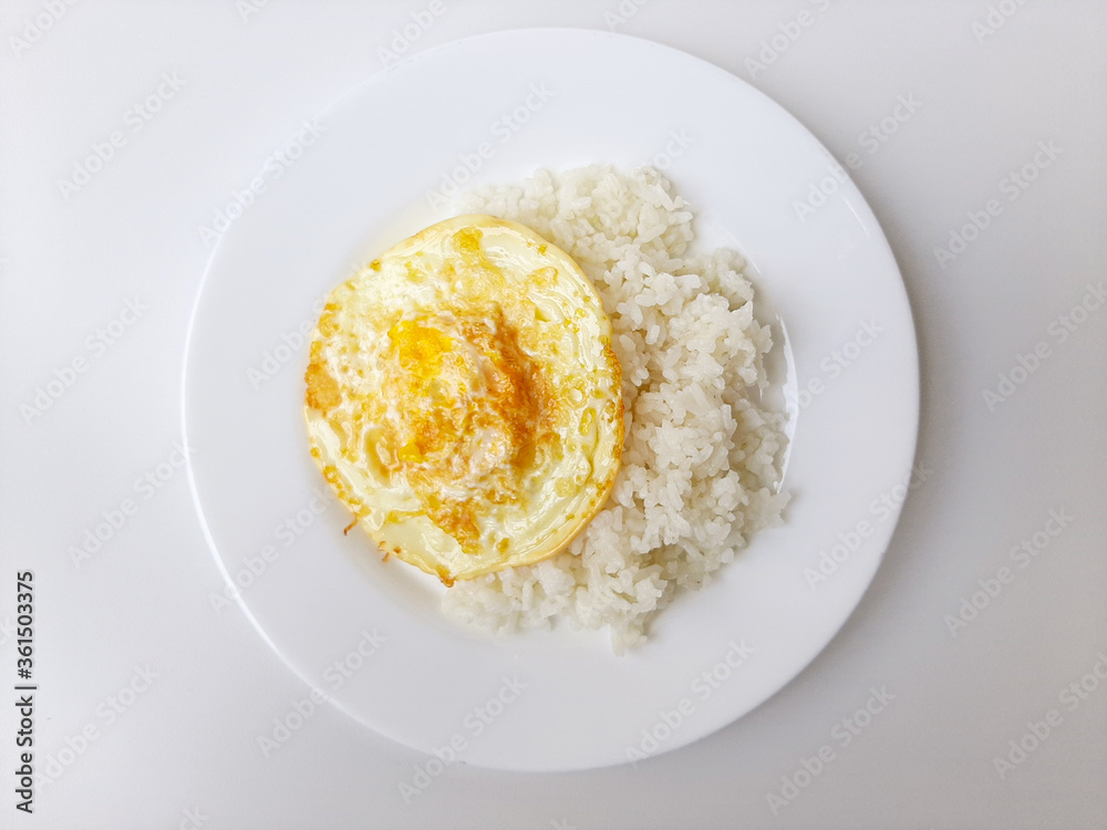 Fried egg or overcooked sunny side up, served with white rice, on a white plate, isolated in white background Fried egg or overcooked sunny side up, served with white rice, on a white plate, isolated in white background