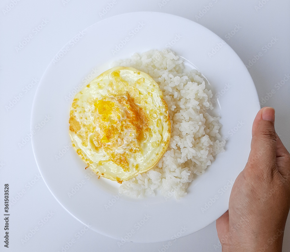 Fried egg or overcooked sunny side up, served with white rice, on a white plate, isolated in white background Fried egg or overcooked sunny side up, served with white rice, on a white plate, isolated in white background