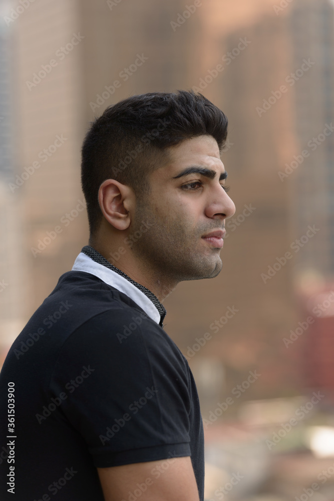 Face of young handsome Indian man thinking in the city Face of young handsome Indian man thinking in the city