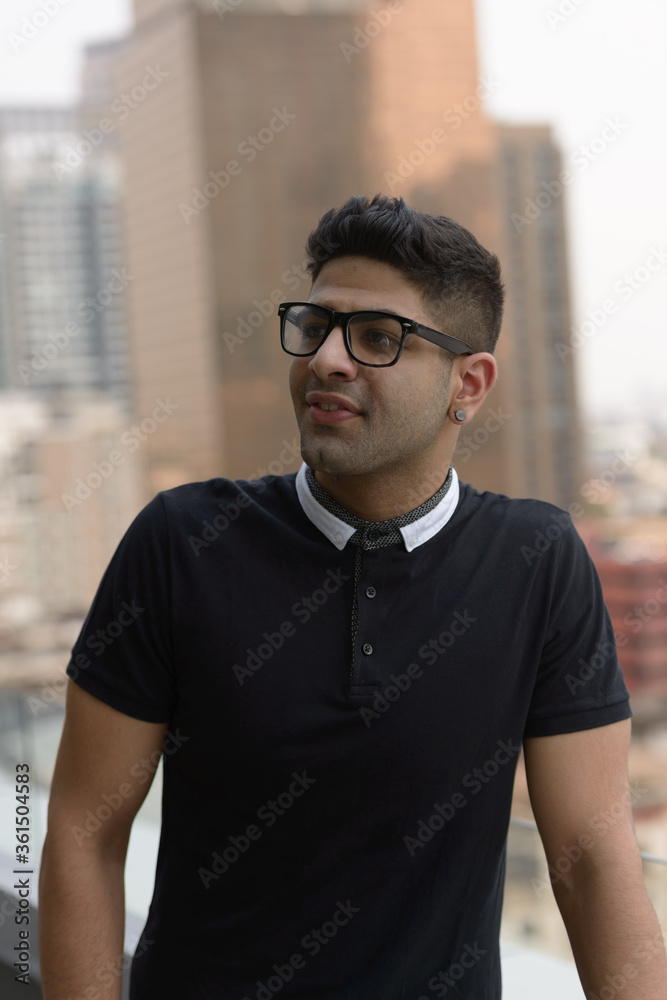 Happy young handsome Indian man with eyeglasses thinking in the city Happy young handsome Indian man with eyeglasses thinking in the city