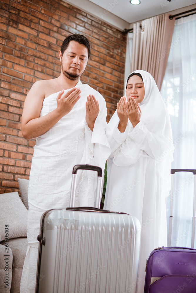 Muslim couple wear ihram praying open their arm wearing ihram before