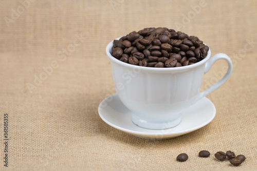 Coffee beans in a white coffee mug placed on a brown background