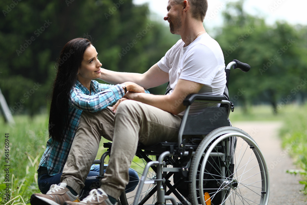 Portrait of sweet couple spending time together on fresh air in park. Lovely woman and man chatting and hugging. Happy relationship and disabled people concept