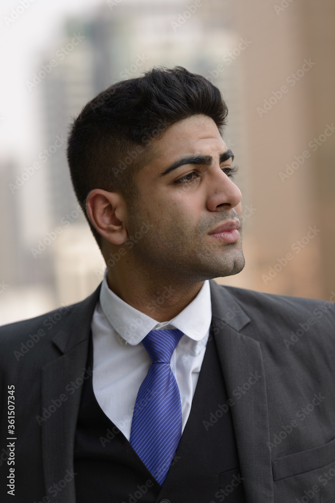 Face of young handsome Indian businessman thinking in the city Face of young handsome Indian businessman thinking in the city