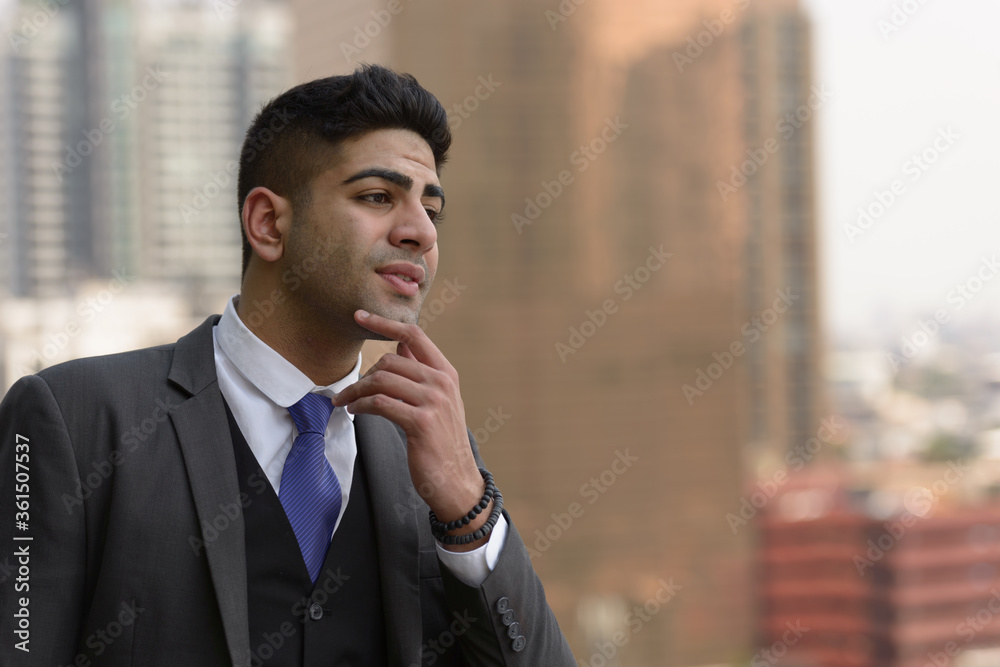 Face of young handsome Indian businessman thinking in the city Face of young handsome Indian businessman thinking in the city