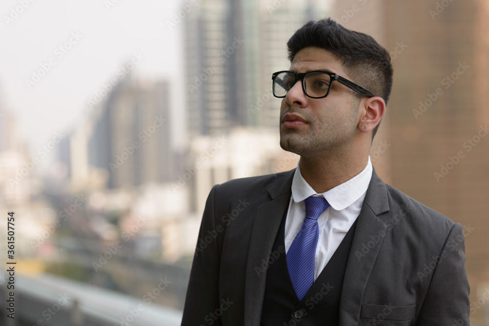 Young handsome Indian businessman with eyeglasses thinking in the city Young handsome Indian businessman with eyeglasses thinking in the city