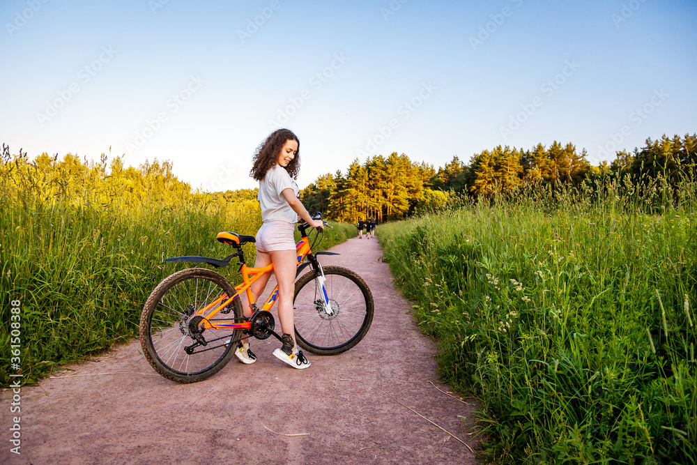 Athletic girl on a bike on the road in the field.