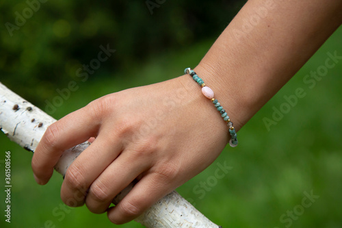 Outdoor detail of female hand wearing mineral crystals round beads bracelet