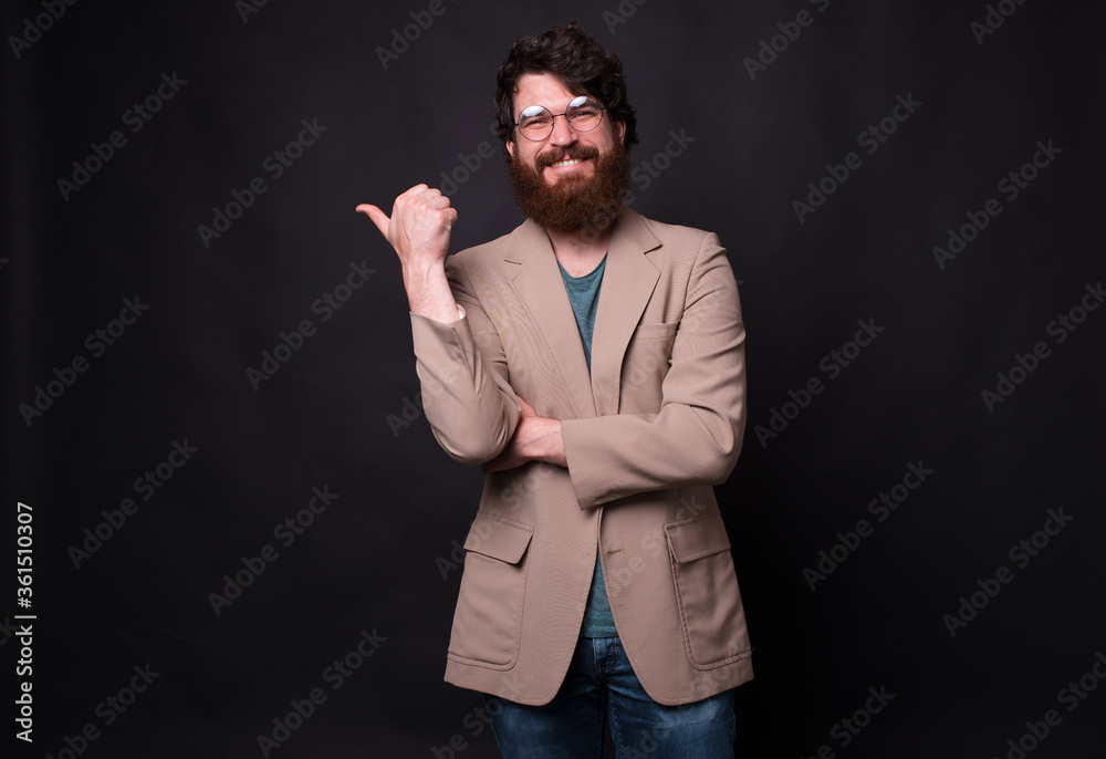 Portrait of happy bearded man in casual standing over black background and pointing at the corne. Portrait of happy bearded man in casual standing over black background and pointing at the corne.