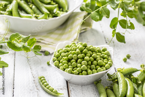 Green raw peas and pods in pocelain bow isolated on wooden table photo