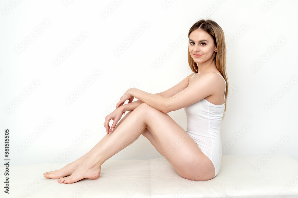 Beautiful young slim caucasian woman in white lingerie or underwear sitting on a white background