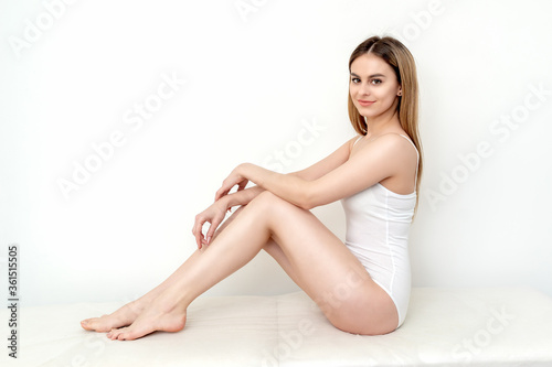 Beautiful young slim caucasian woman in white lingerie or underwear sitting on a white background
