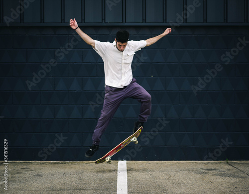 Konstfotografi Young athletic male doing tricks with a skateboard at a skate park during daytim