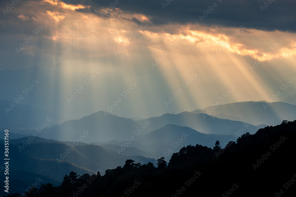 Ray of sunlight shining through clouds to mountains.