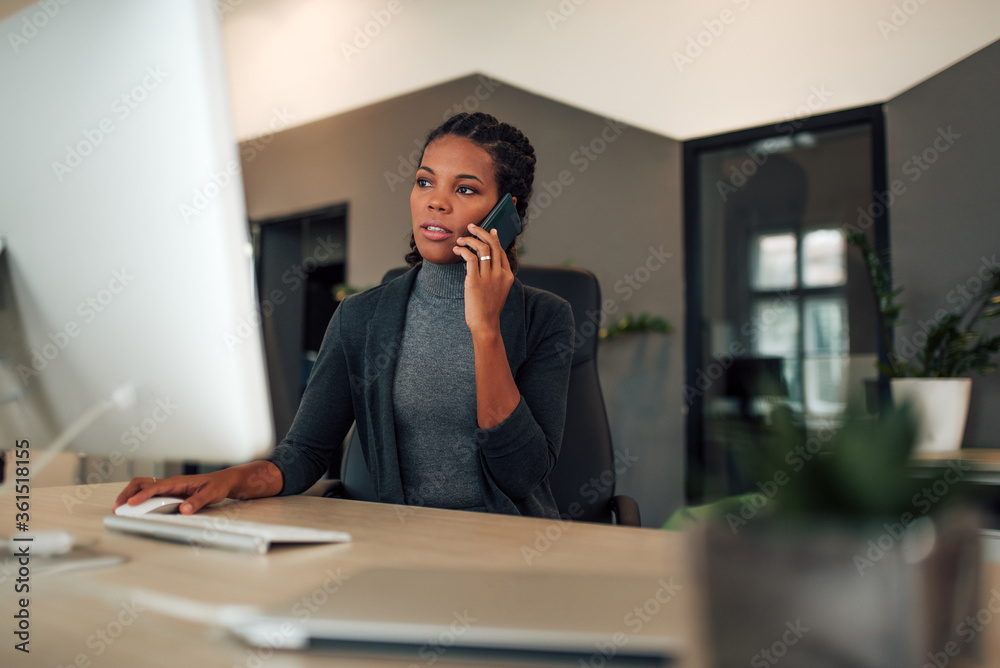 Portrait of a businesswoman working on computer and talking on smart phone. Portrait of a businesswoman working on computer and talking on smart phone.