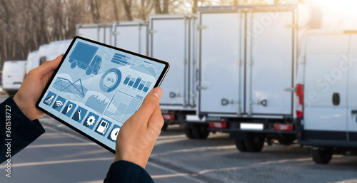 Foto Manager with a digital tablet on the background of trucks