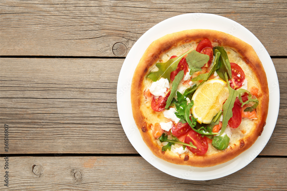 Margherita Italian pizza with cheese and tomato garnished with on grey wooden table with copy space Margherita Italian pizza with cheese and tomato garnished with on grey wooden table with copy space