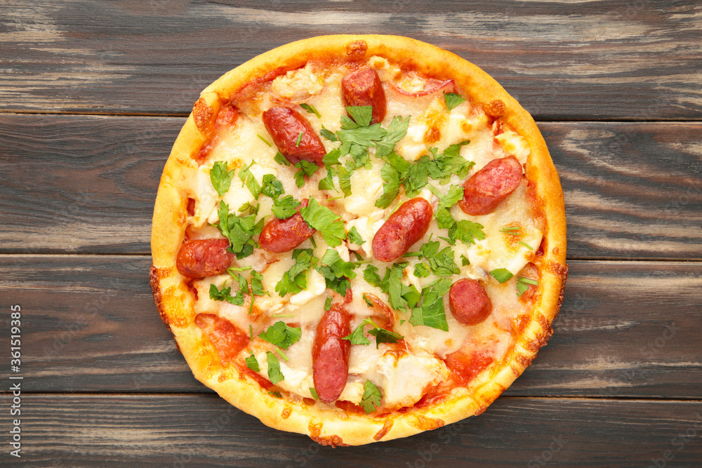 Tasty Italian pizza with sausage on brown wooden table