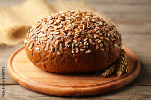 Wholegrain rye bread on a cutting board on grey background