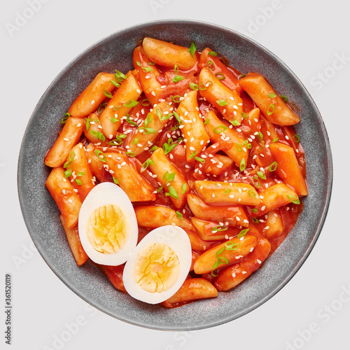 Tteokbokki with eggs in gray bowl isolated on white. Tteok-bokki is a korean cuisine dish of rice cakes and chilli sauce. Asian food. Top view photo