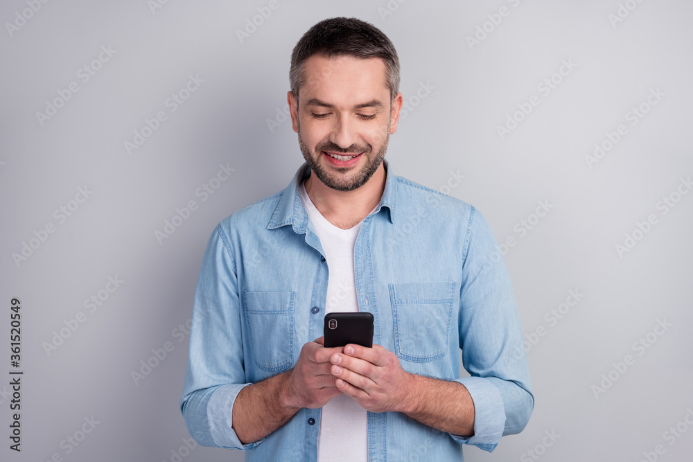 Close-up portrait of his he nice attractive content focused cheerful cheery guy using modern technology cell browsing web isolated over gray light pastel color background Close-up portrait of his he nice attractive content focused cheerful cheery guy using modern technology cell browsing web isolated over gray light pastel color background