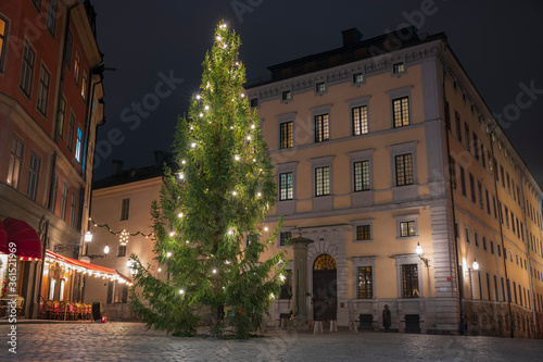 An evergreen tree, lighted for the Christmas holiday at a square on the compact island of Gamla Stan, Stockholm, Sweden's old town, with cobbled streets and colorful 17th- and 18th-century buildings. 
