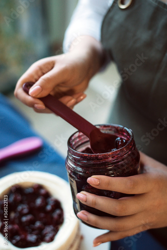 Cook puts jam with berries on the cake with cream. The pastry chef puts the jam and decorate the cake