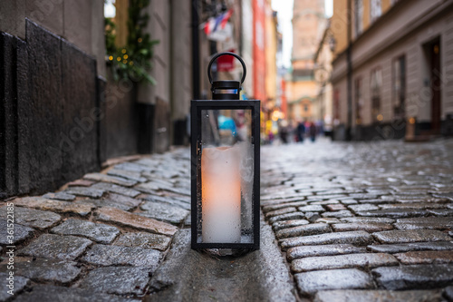 A lantern with a glowing candle rests on a cobblestone street corner in Gamla stan, the old town of Stockholm, Sweden. 