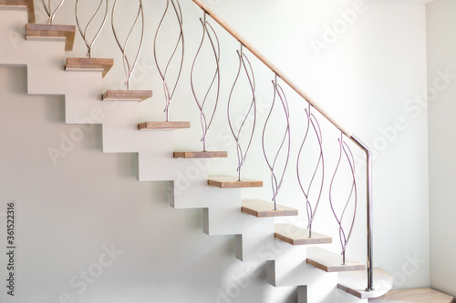 Elegance contemporary designed stairs in a white modern room of luxury apartment. No people, natural lighting.