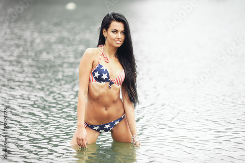 Woman on the beach in a swimsuit with an American flag having fun