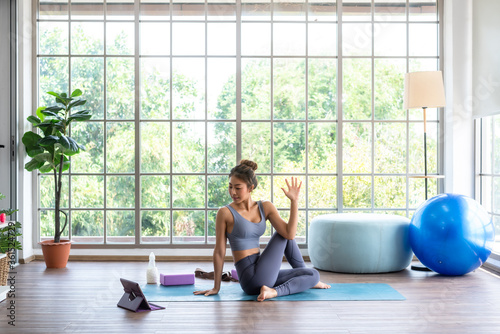 Asian woman practising yoga at home online use tablet attend online course photo