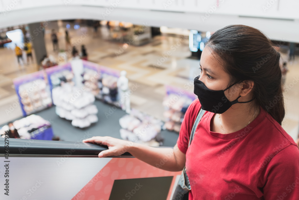Asian women wear medical masks and are using escalators in shopping