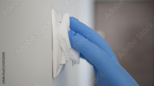 Man Wearing Protection Gloves Cleaning and Disinfecting Light Switch from the Office Room Using Disinfectant Against Covid-19  Viruses