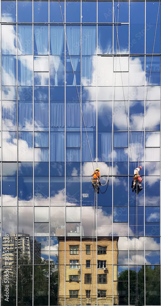 Obraz premium two working climbers on a glass wall of a high-rise building