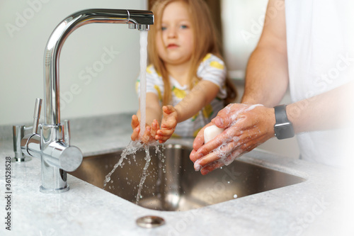 Father and daughter washing their hands above the sink in a kitchen