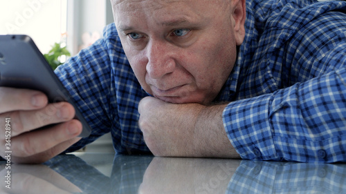 Sad Elderly Person Isolated in Quarantine at Home Looking Bored and Disappointed to a Cell Phone
