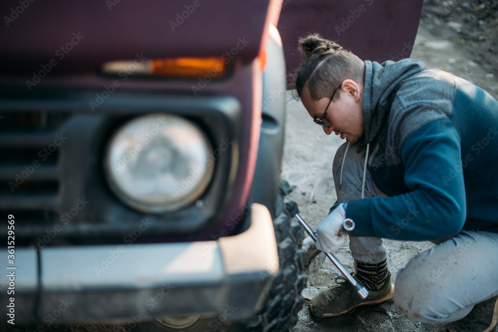 A man repairs a car, puts wheels, changes seasonal tires A man repairs a car, puts wheels, changes seasonal tires