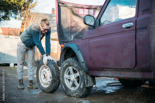 A man repairs a car, puts wheels, changes seasonal tires