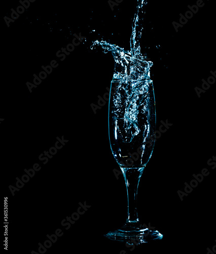Splashes and drops of water in a glass are isolated on a black background.