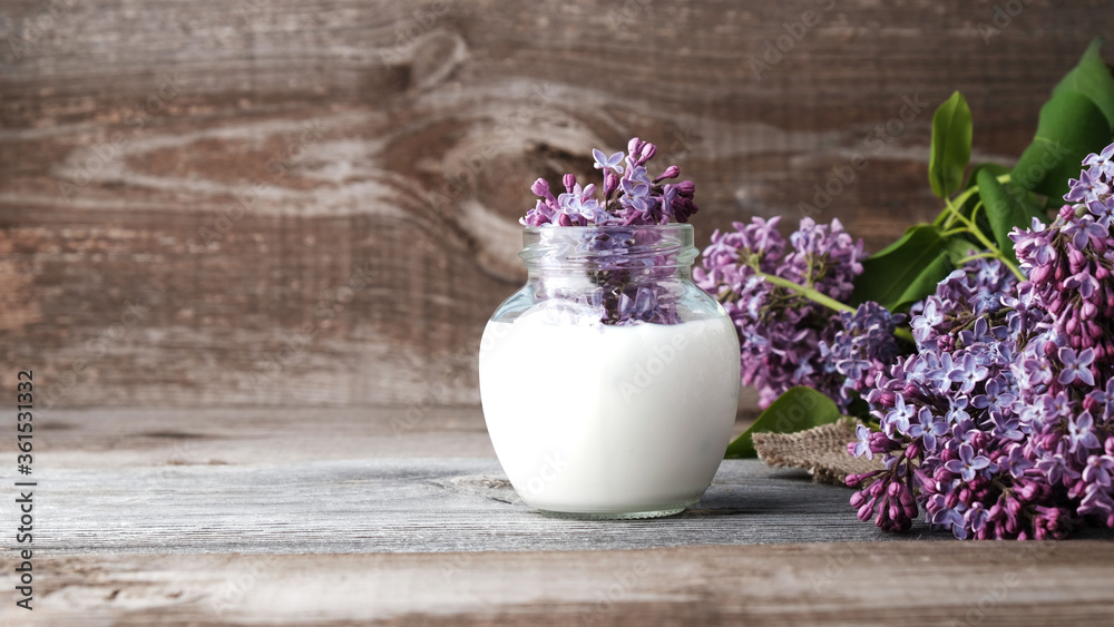 Natural cosmetics concept, lilac flowers in jar with milk on wooden background with copy space Natural cosmetics concept, lilac flowers in jar with milk on wooden background with copy space