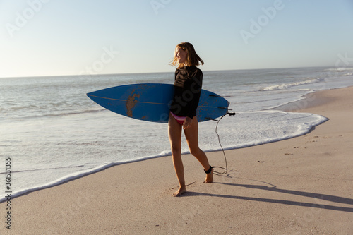 Woman with surfboard walking on the beach