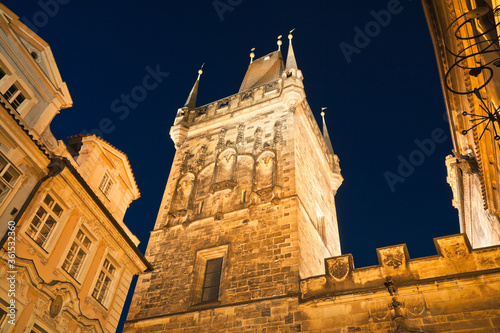 Look up the illuminated Lesser town tower of Charles bridge at twilight with its typical gothic spikes