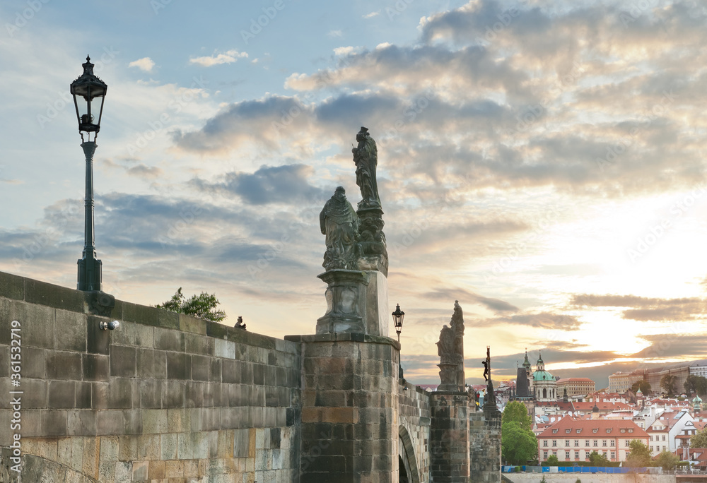 Fototapeta premium Side view of stone Charles bridge and its sculptures at sunset during lockdown