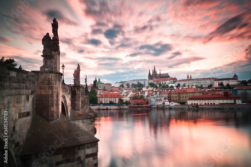 Side view of Charles bridge and Prague castle during twilight with red windy sky