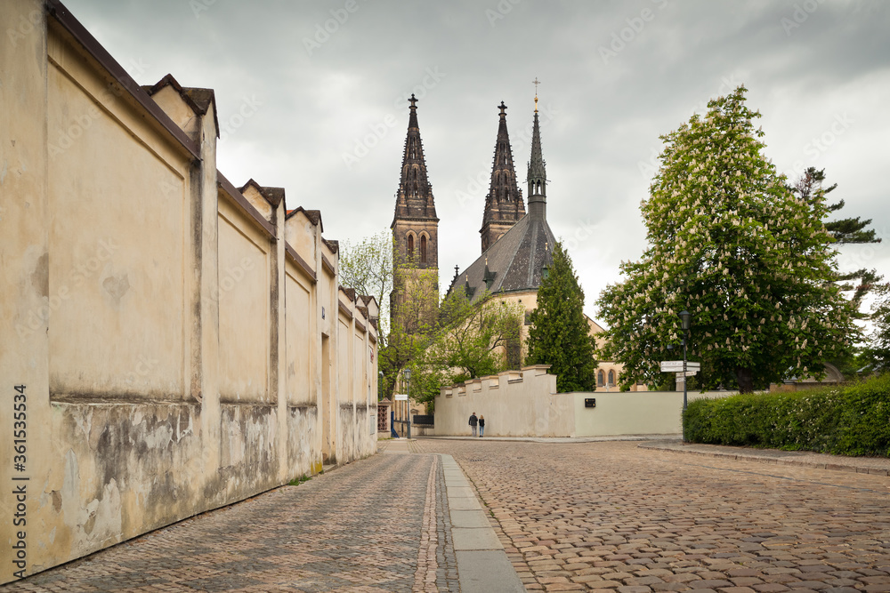 Medieval Vysehrad church from a street with wall optically leading eye towards it taken on a cloudy lockdown day with no people