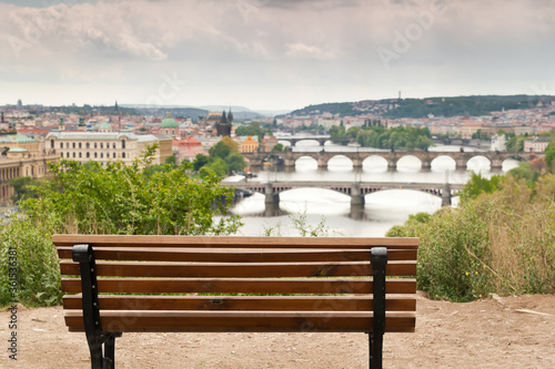 Empty bench at a beautiful vista point in Letna, Prague with a blurred view of the many bridges of Prague and parts of the town