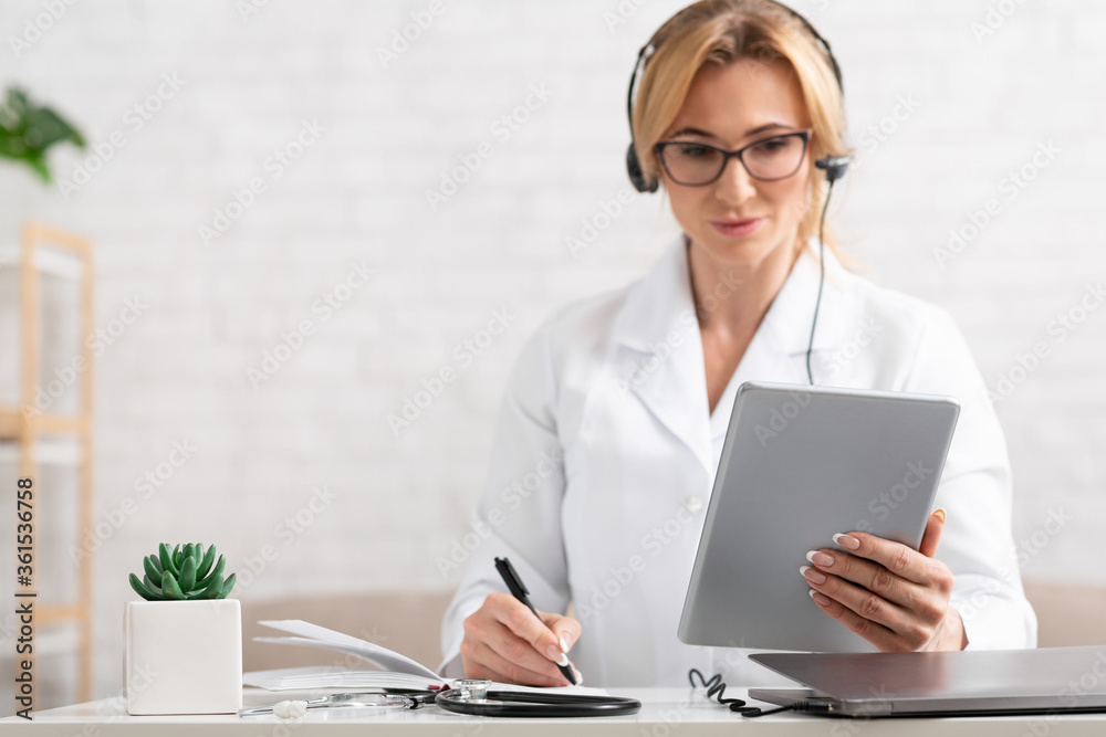 List of symptoms. Woman doctor with headphones holding tablet in hands List of symptoms. Woman doctor with headphones holding tablet in hands