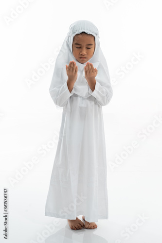 Muslim kid praying and wearing ihram isolated over white